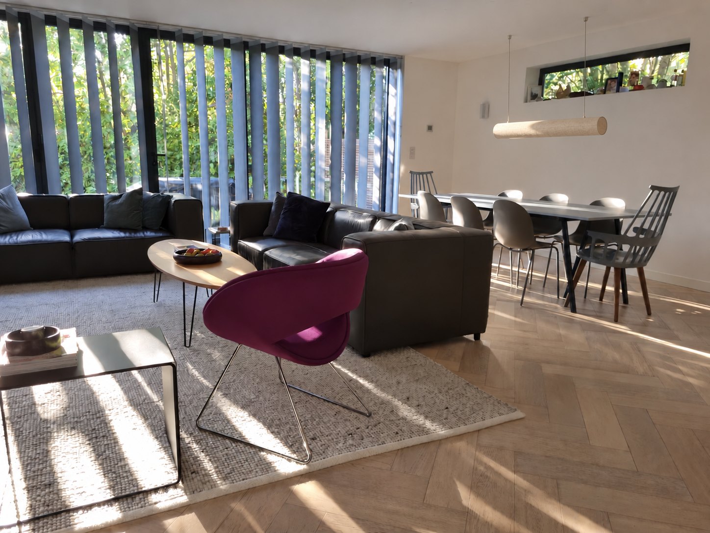 Open-plan living and dining room with a purple armchair, leather sofas and herringbone oak floor